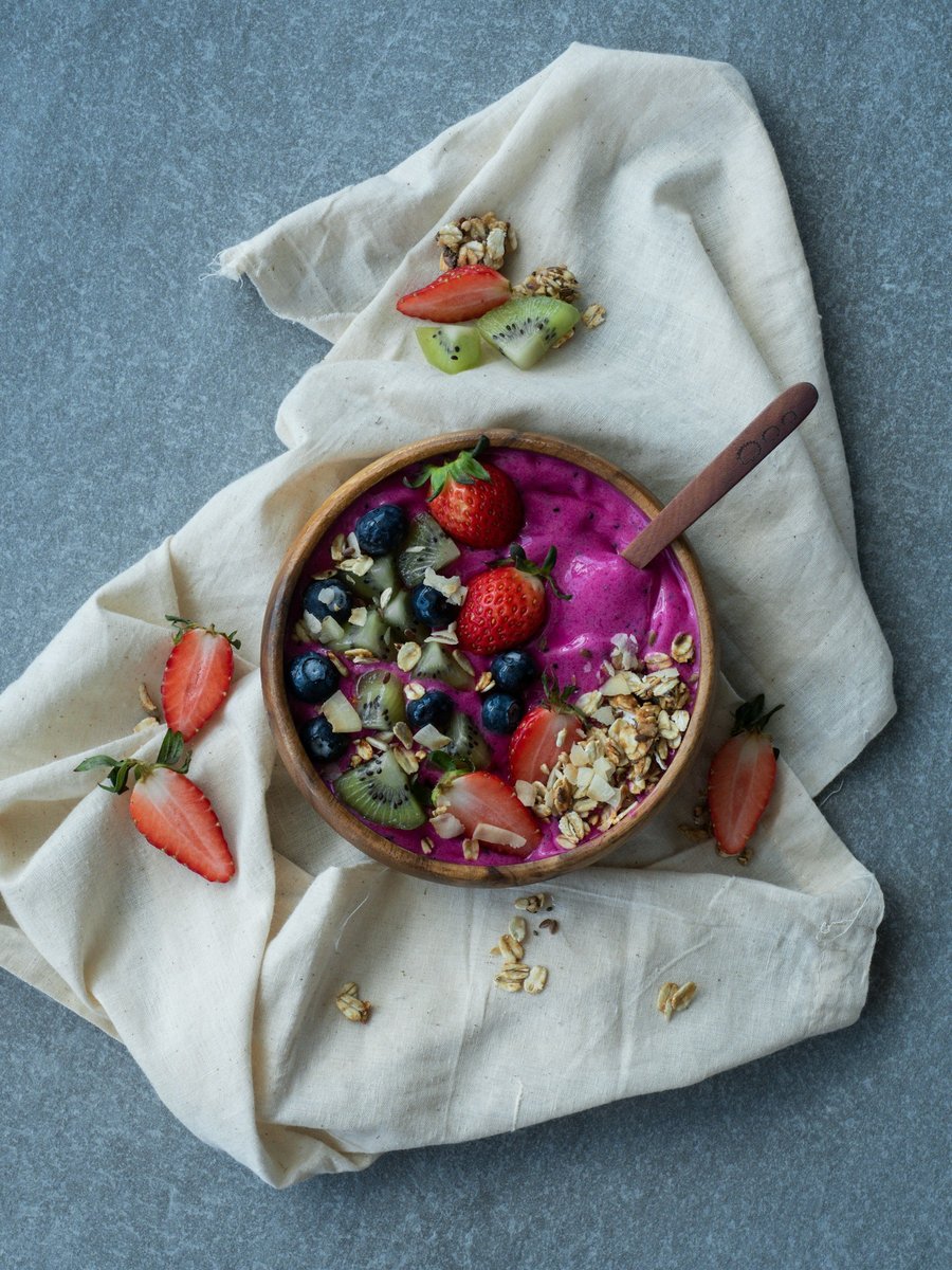 Bol de smoothie aux fruits rouges posé sur un linge, fond bleu-gris