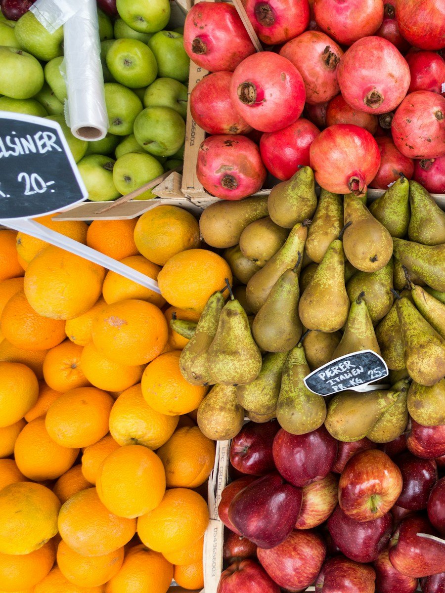 Cagettes de grenades, de poires, d'oranges et de pommes vues de dessus