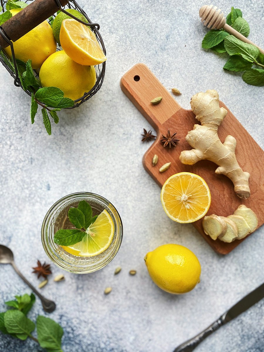 Gingembre, citrons, menthe et verre d'eau citronnée sur un plan gris