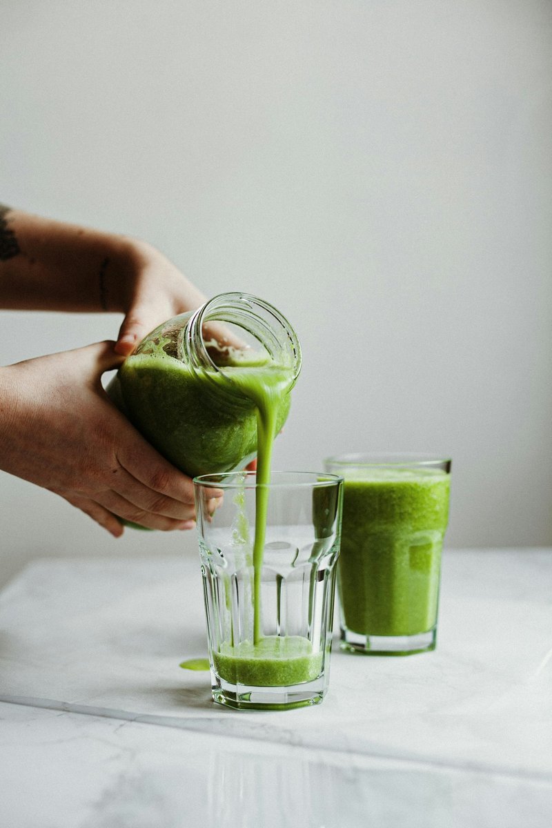 Jus vert versé d'un bocal en verre dans un verre